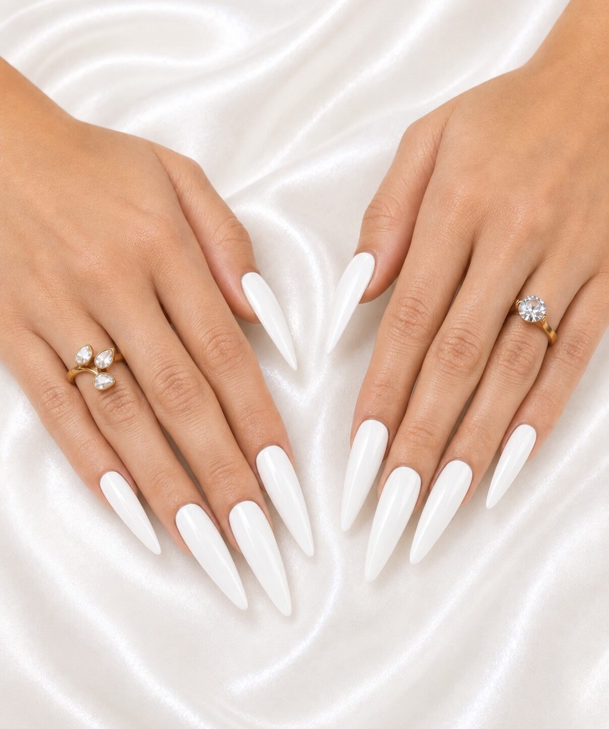 Extensiones: uñas stiletto blancas muy largas, forma lograda en la cita.