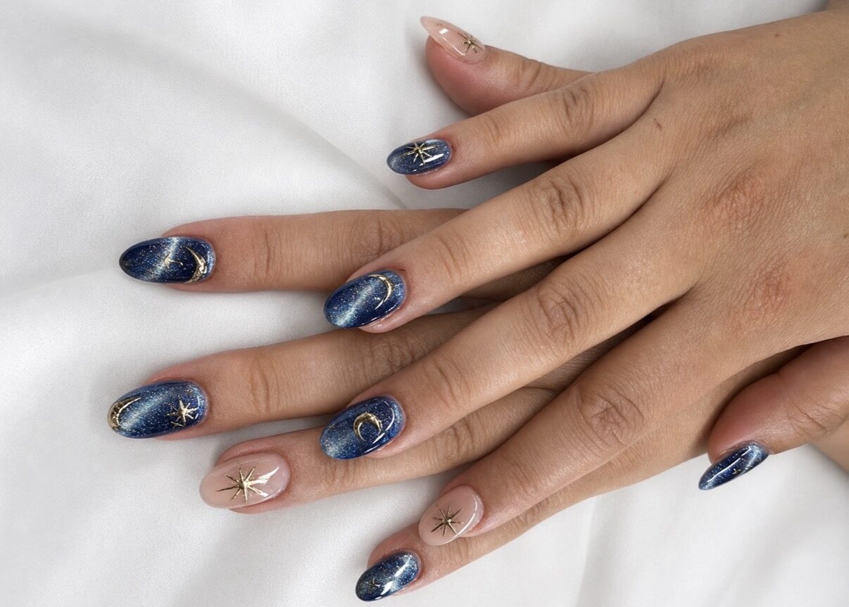 Nail art: fondo azul noche marmoleado, estrellas y lunas doradas pintadas a mano.