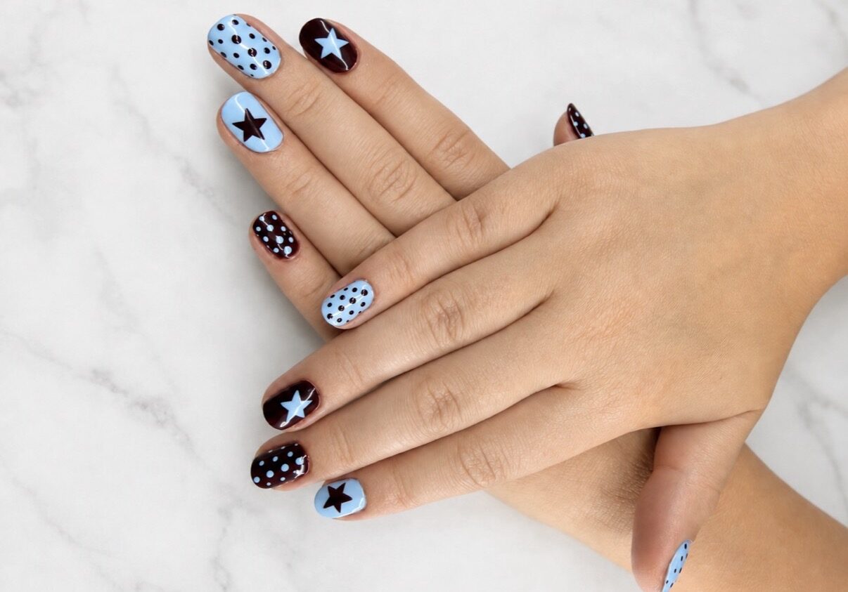 Nail art azul cielo y negro: estrellas, lunares y uñas lisas alternadas.