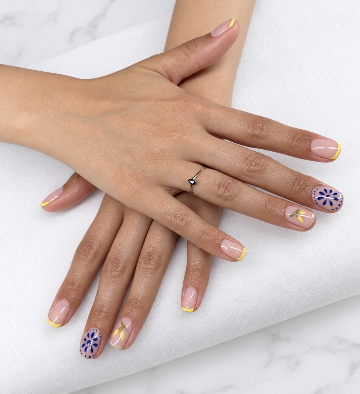Nail art: francesa amarilla y flores azules pintadas a mano en dos uñas.